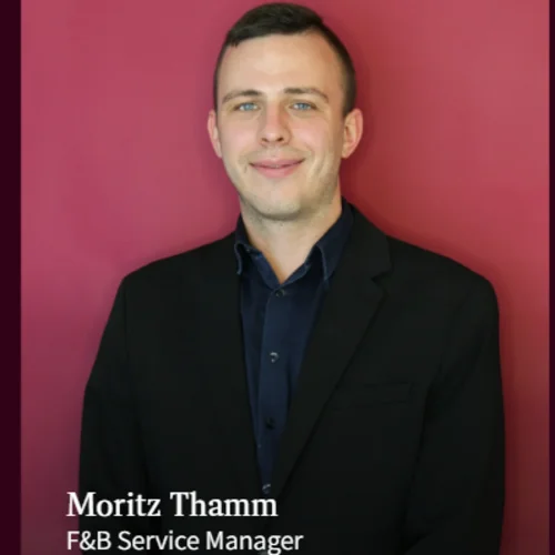 Portrait of Moritz Thamm, F&B Service Manager, against a red background