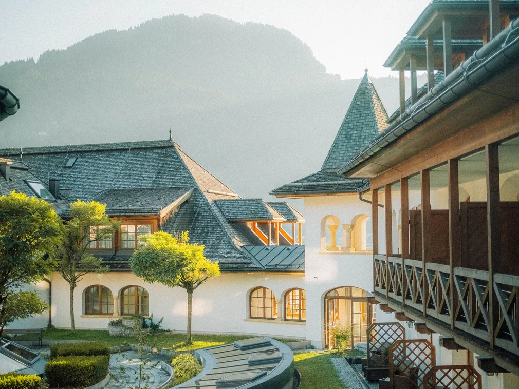 Historic building with garden and mountains in the background lit by sunlight