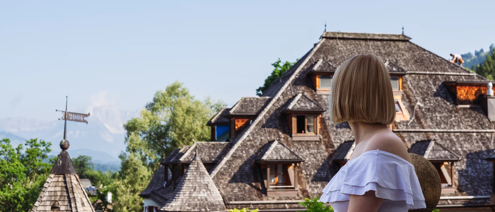 Frau auf der Terrasse im Hintergrund das Schloss und blauer Himmel