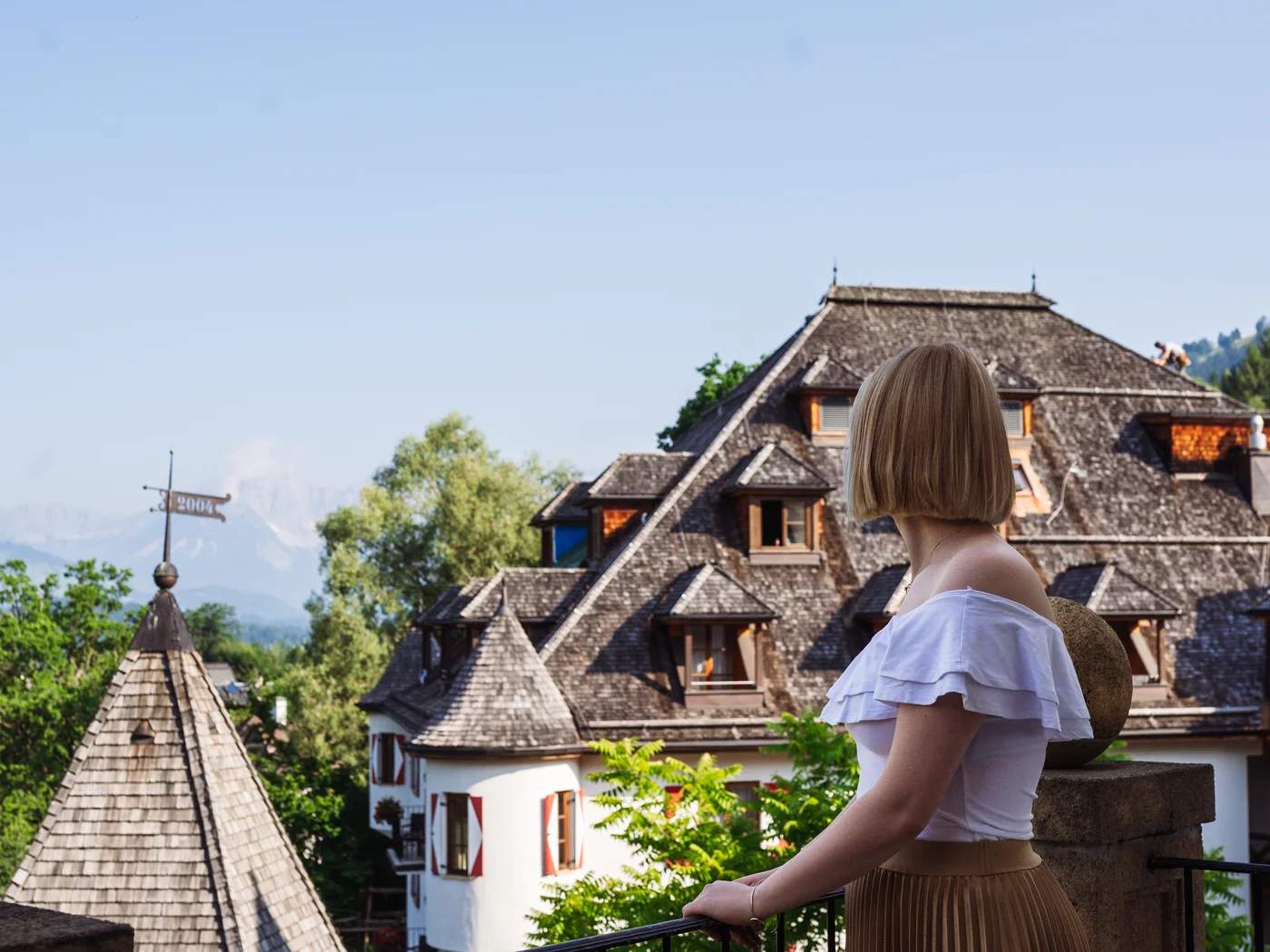 Frau auf der Terrasse im Hintergrund das Schloss und blauer Himmel