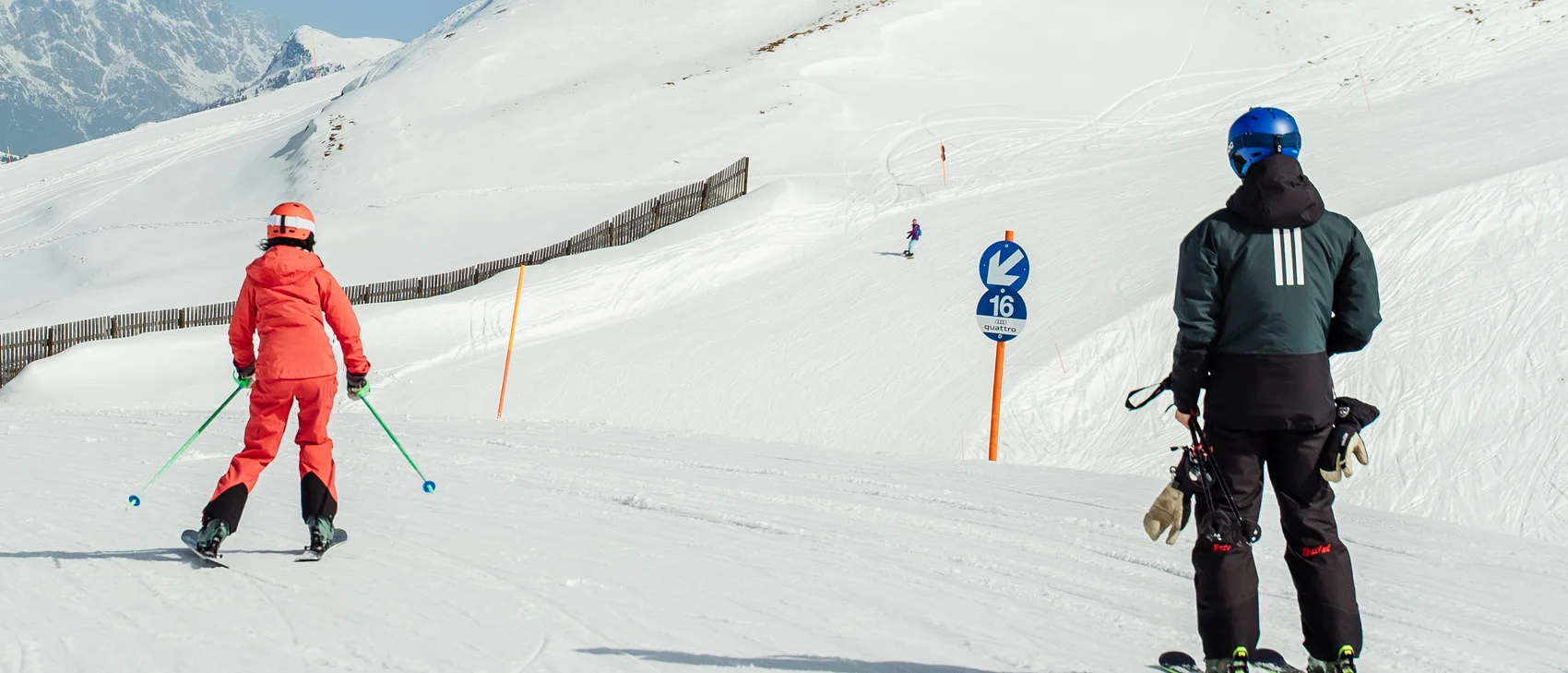 Blaue Skipiste mit Menschen die Skifahren und Kaiserwetter Blaue Skipiste mit Menschen die Skifahren und Kaiserwetter