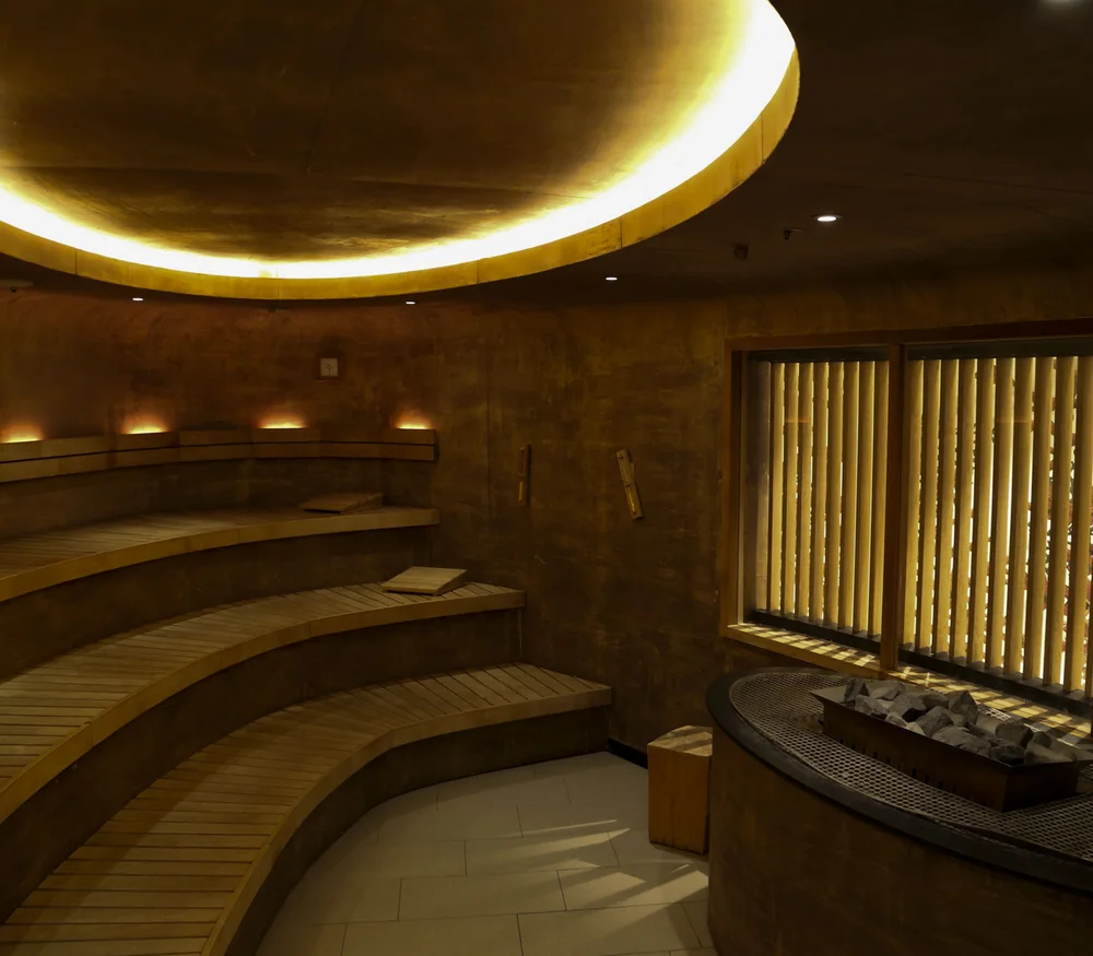 Vollmond-Spa-Nacht im Schlosshotel Kitzbühel Innenraum einer modernen Sauna mit gebogenen Holzliegen und indirekter Beleuchtung