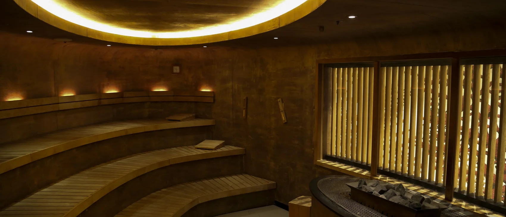 Vollmond-Spa-Nacht im Schlosshotel Kitzbühel Innenraum einer modernen Sauna mit gebogenen Holzliegen und indirekter Beleuchtung