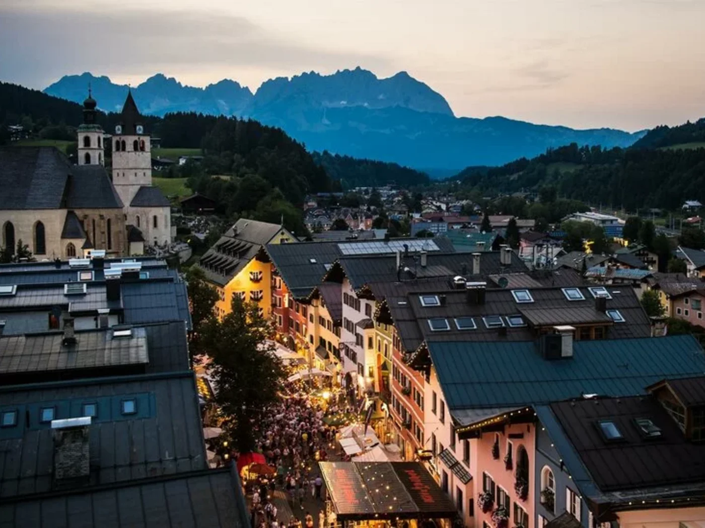 View of illuminated old town with church and mountains at dusk