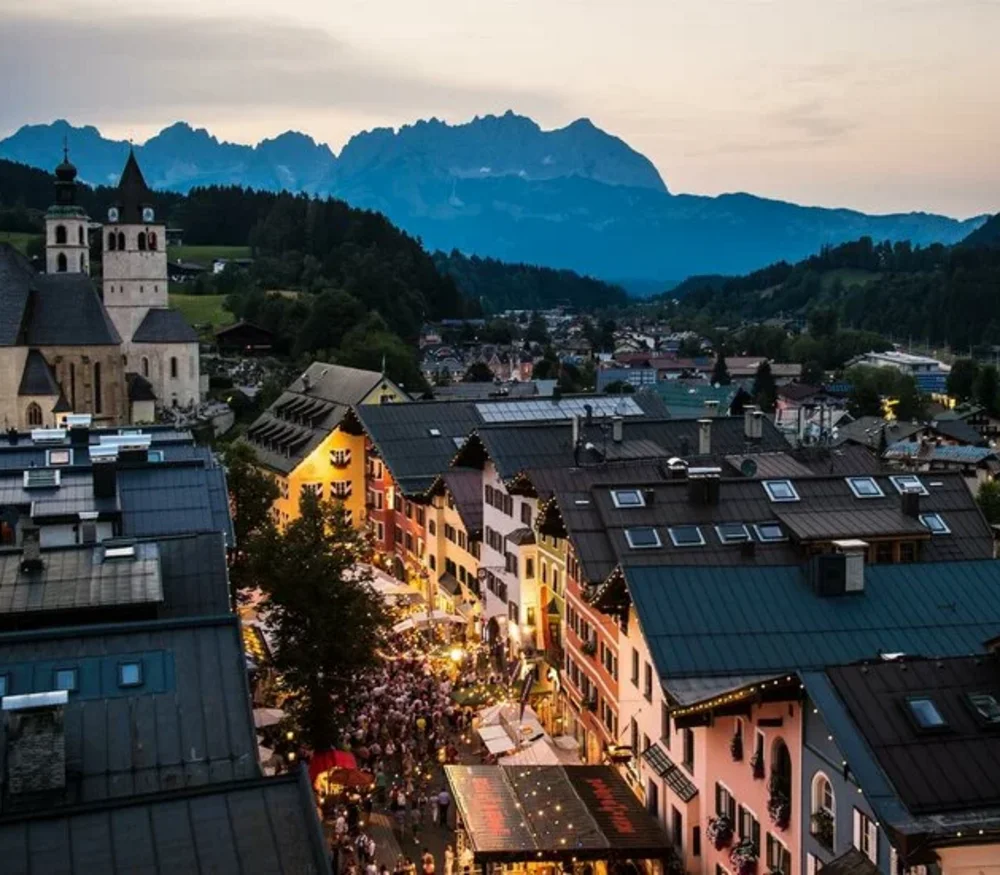 Kitzbüheler Adventmarkt Blick auf beleuchtete Altstadt mit Kirche und Bergen im Abendlicht