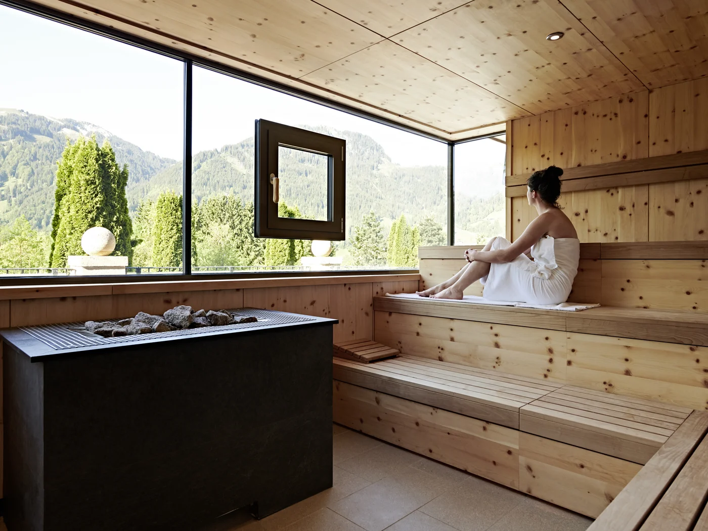 Frau in Sauna genießt die Aussicht auf die Berge Frau in Sauna genießt die Aussicht auf die Berge