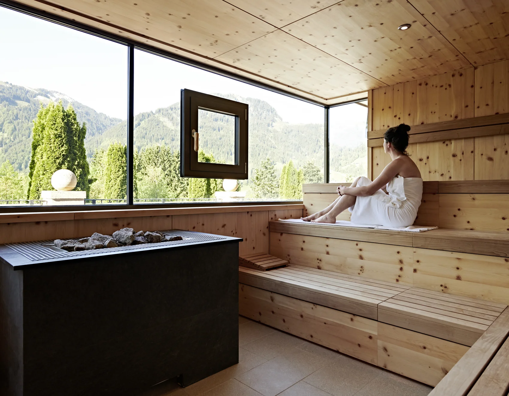 Frau in Sauna genießt die Aussicht auf die Berge Frau in Sauna genießt die Aussicht auf die Berge