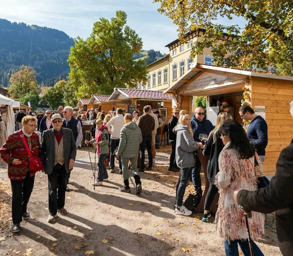 Persone che visitano un mercato con casette di legno e tende in autunno