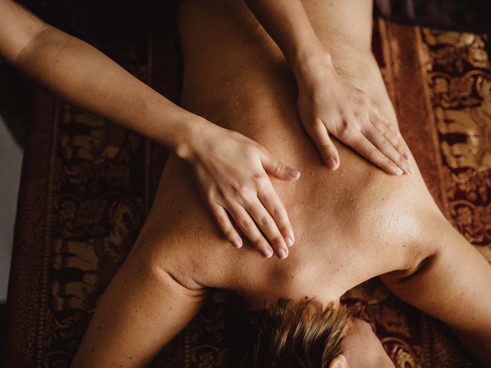 Person receiving a back massage on a brown massage table