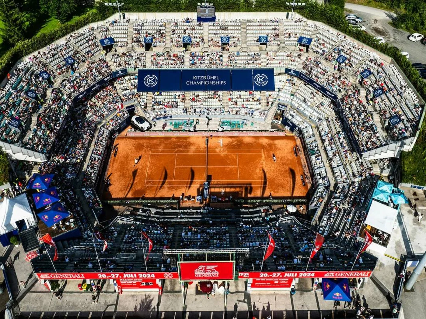Luftaufnahme eines Tennisstadions mit rotem Sandplatz und Zuschauern bei Kitzbühel Championships