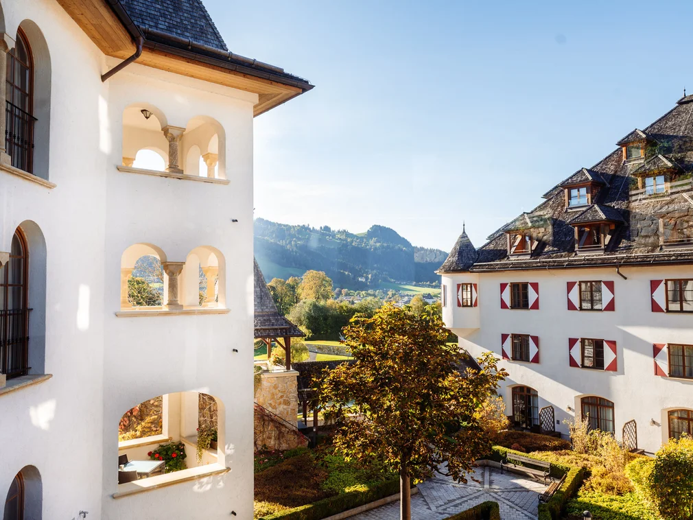 View of historic building complex with courtyard and mountains in background