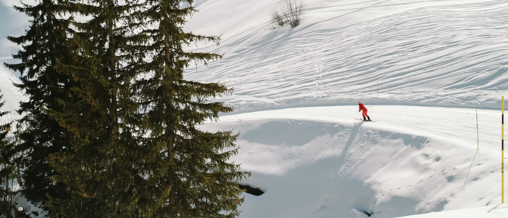 Hahnenkamm-Vorfieber – Kitzbühel, bevor die Welt zusieht Skifahrer in roter Kleidung fährt auf schneebedecktem Berg neben Tannenbäumen