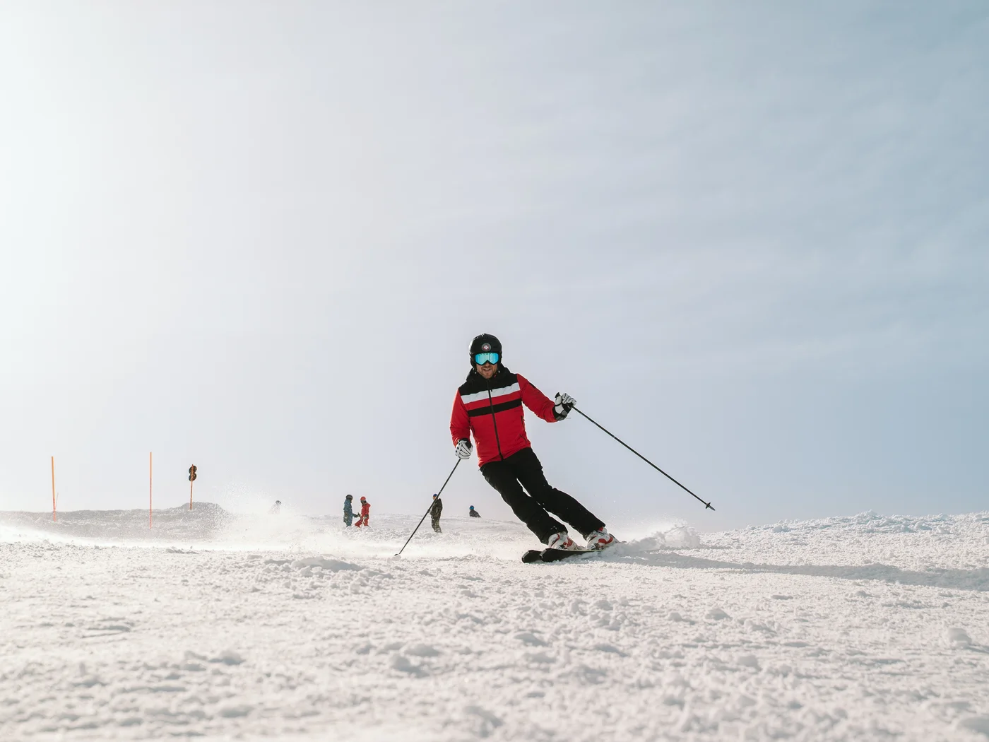 Winter Skier in red jacket skiing on snowy slope under clear sky