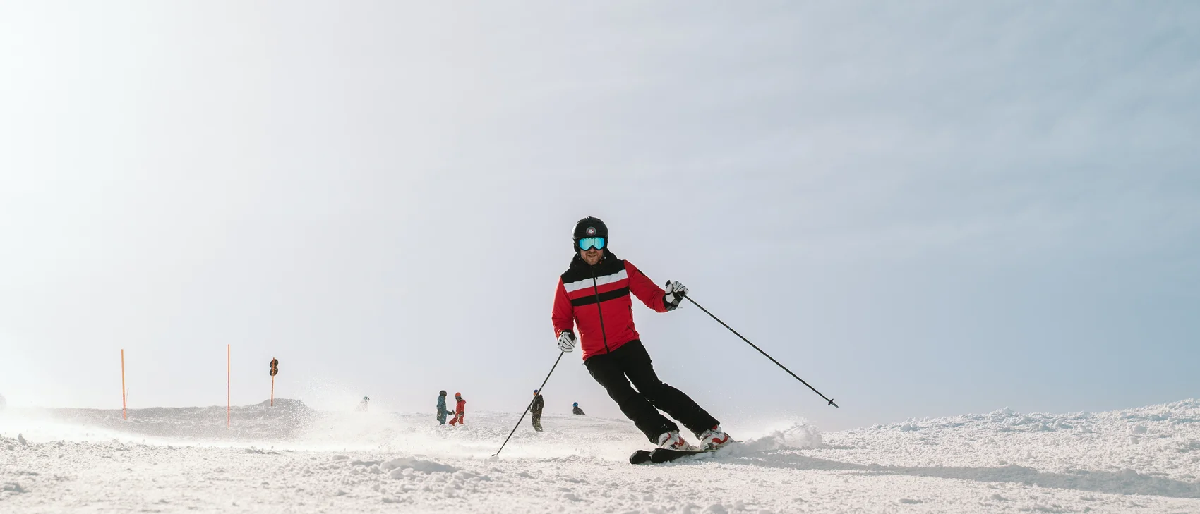 Skier in red jacket skiing on snowy slope under clear sky