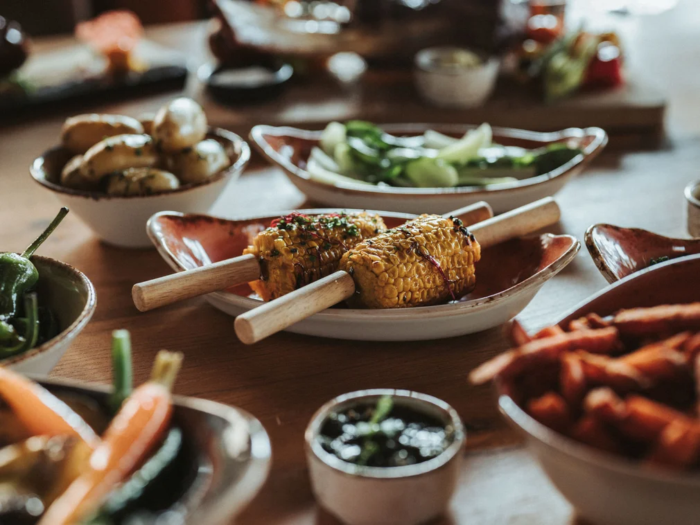 Grilled corn with assorted side dishes on a wooden table