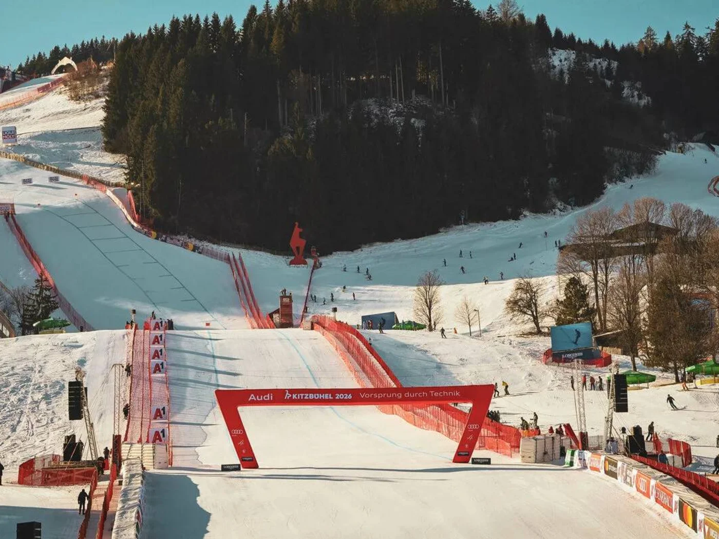 Ski jumping hill and ski area with spectators and trees in the background