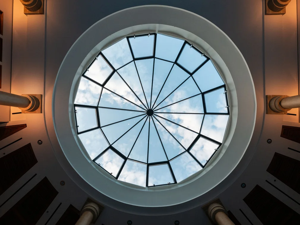 Oval glass ceiling with view of sky and clouds
