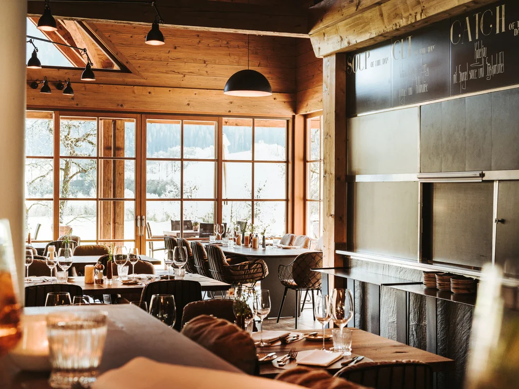 Cozy restaurant with wooden walls and set tables in natural daylight