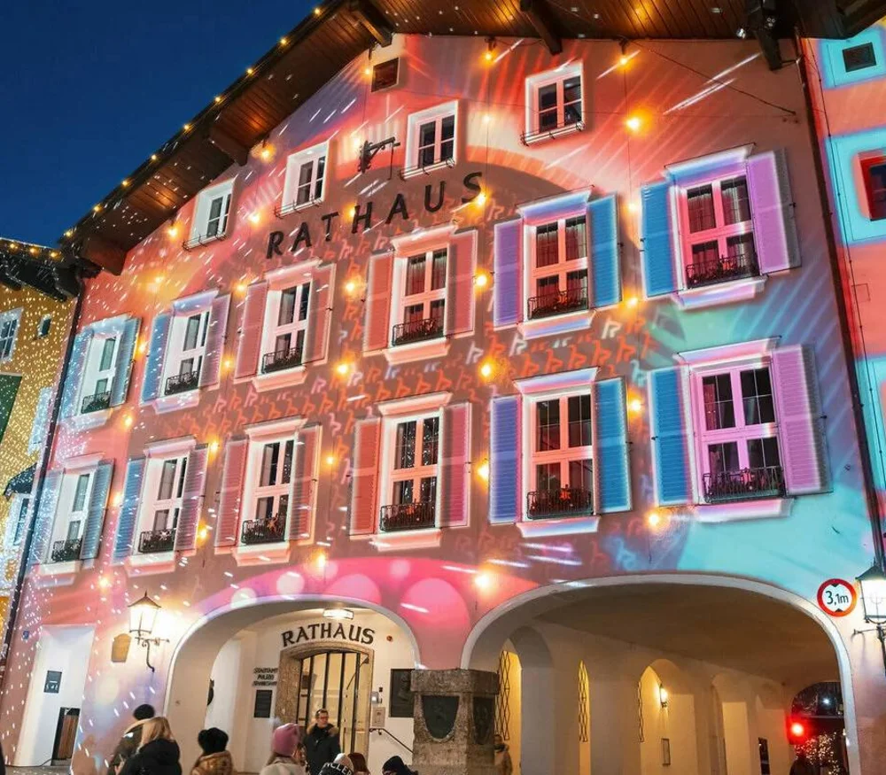 Illuminated town hall building with colorful lights and people in the evening