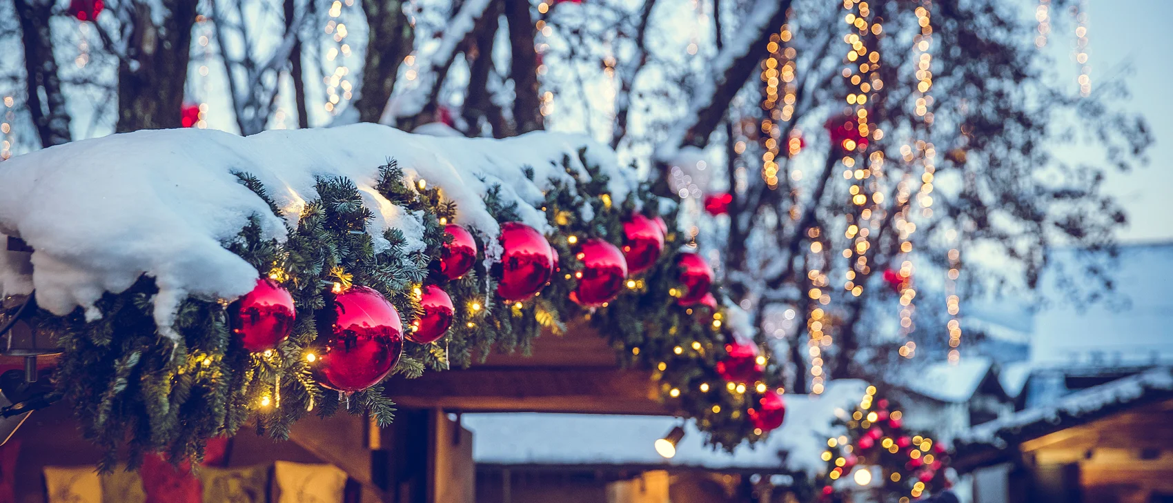 Christmas market with snowy decorations and red baubles on fir branches