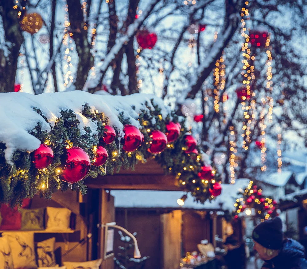 Christmas market with snowy decorations and red baubles on fir branches