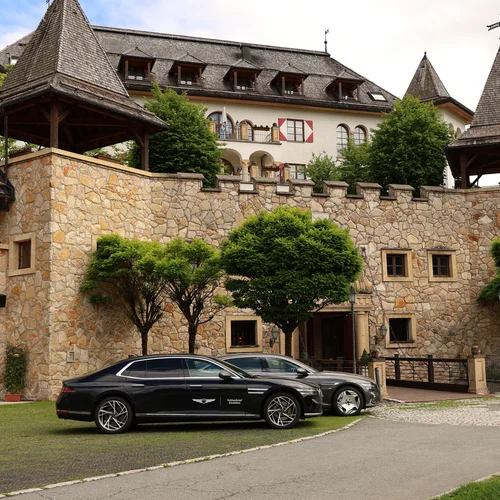 Cosa avete voglia di fare a Kitzbühel oggi? Edificio in pietra con torri e due auto nere parcheggiate davanti
