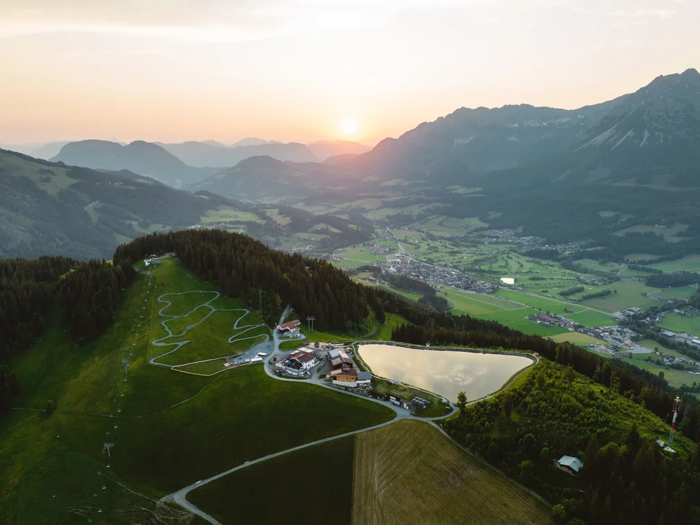 Mountain landscape at sunset with village, lake, and hiking trails