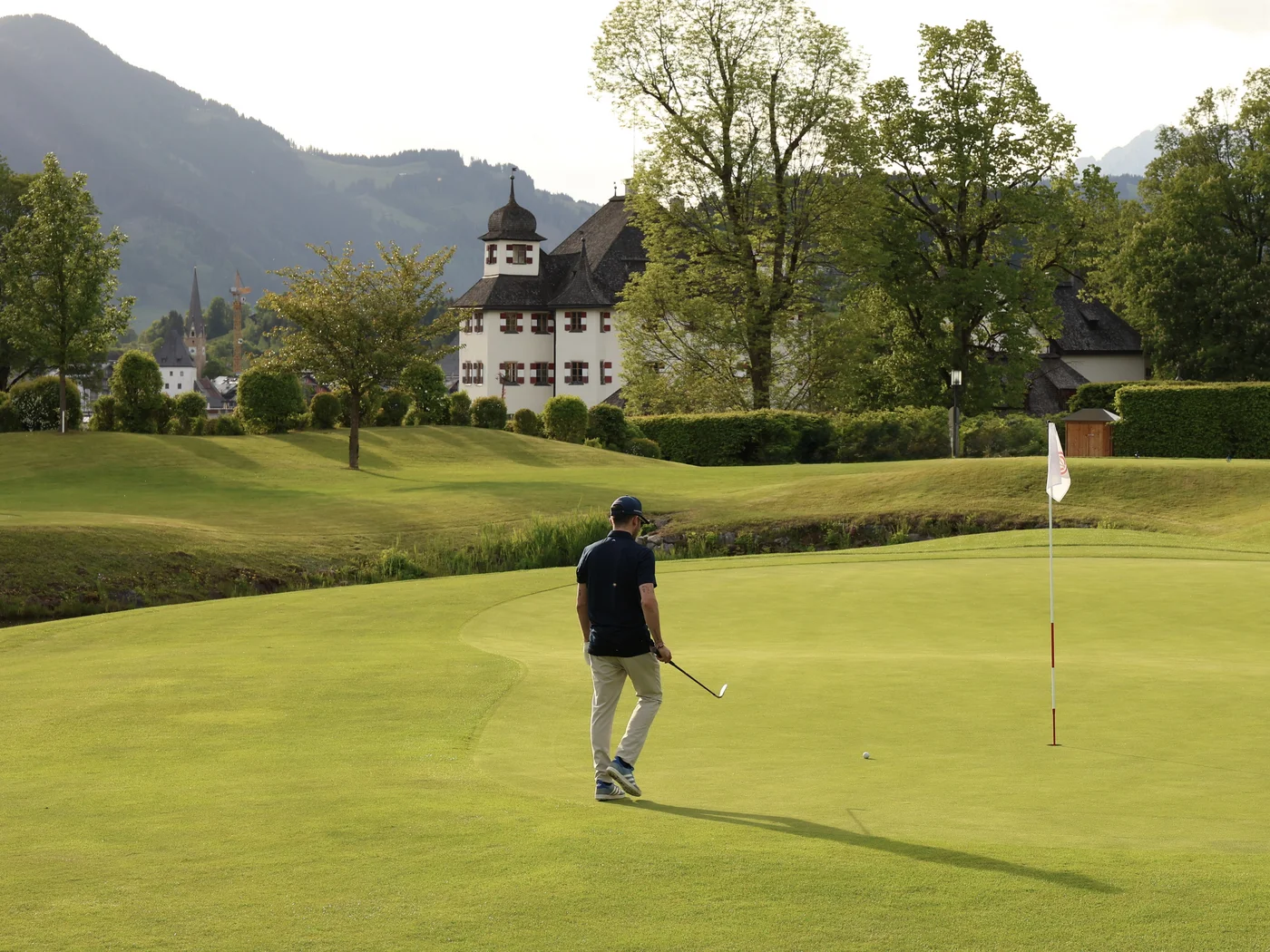[Translate to Italienisch:] Golfer auf Golfplatz mit Schloss im Hintergrund