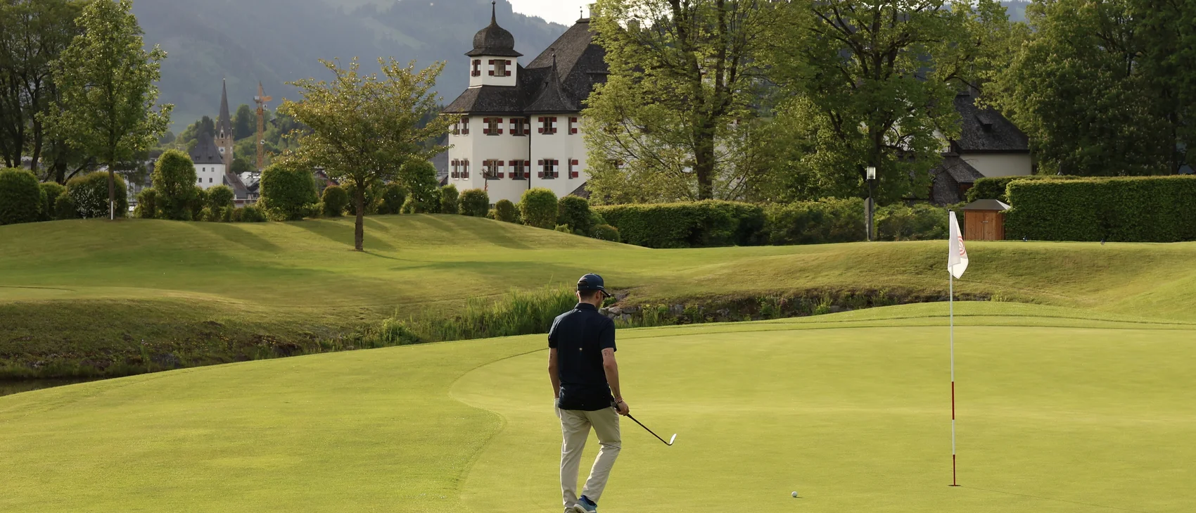 [Translate to Italienisch:] Golfer auf Golfplatz mit Schloss im Hintergrund