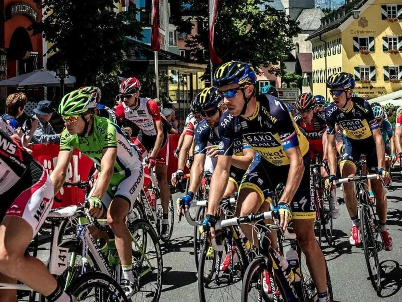 Cyclists racing on a street in a town with colorful buildings