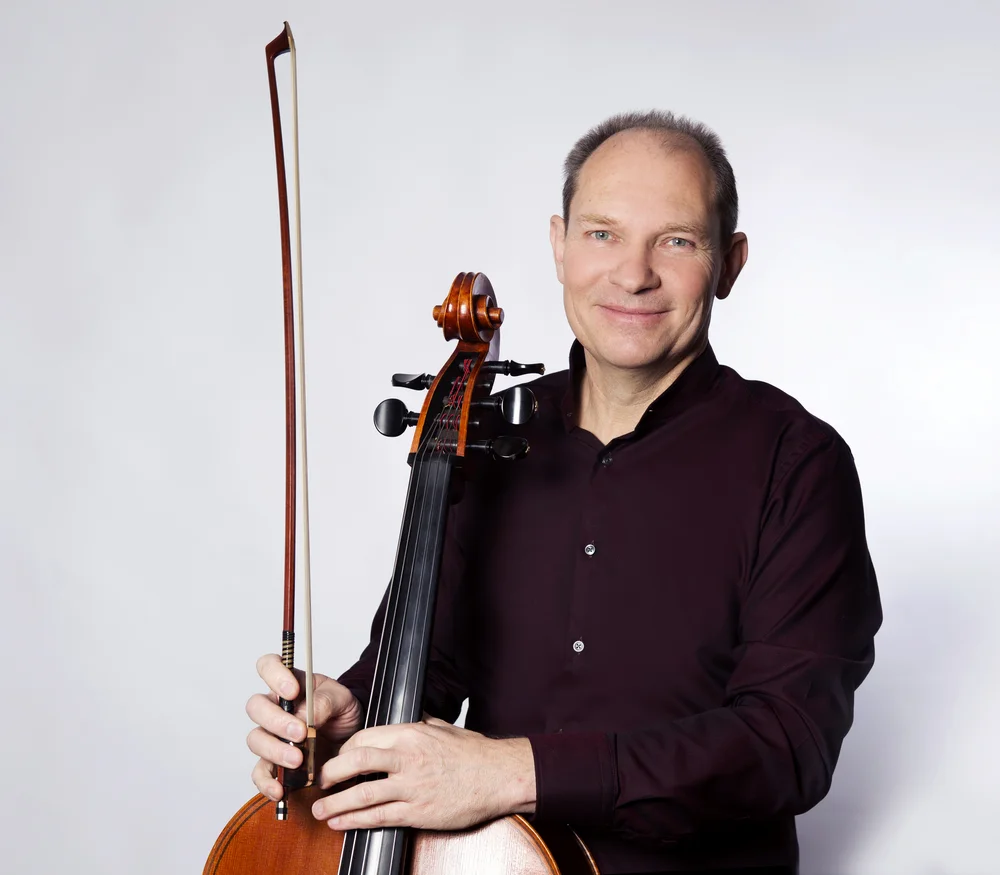 Mann mit Cello und Bogen vor hellem Hintergrund