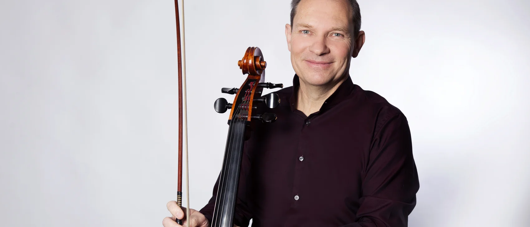 Mann mit Cello und Bogen vor hellem Hintergrund