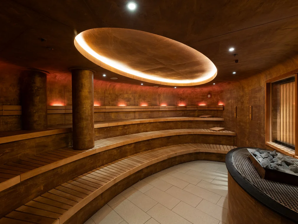 Modern round sauna room with wooden benches and soft ceiling lighting