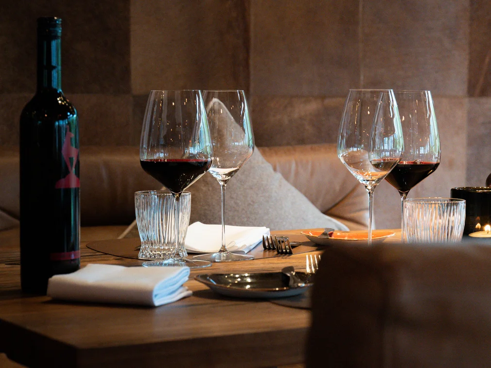 Wine bottle and glasses on set wooden table in restaurant