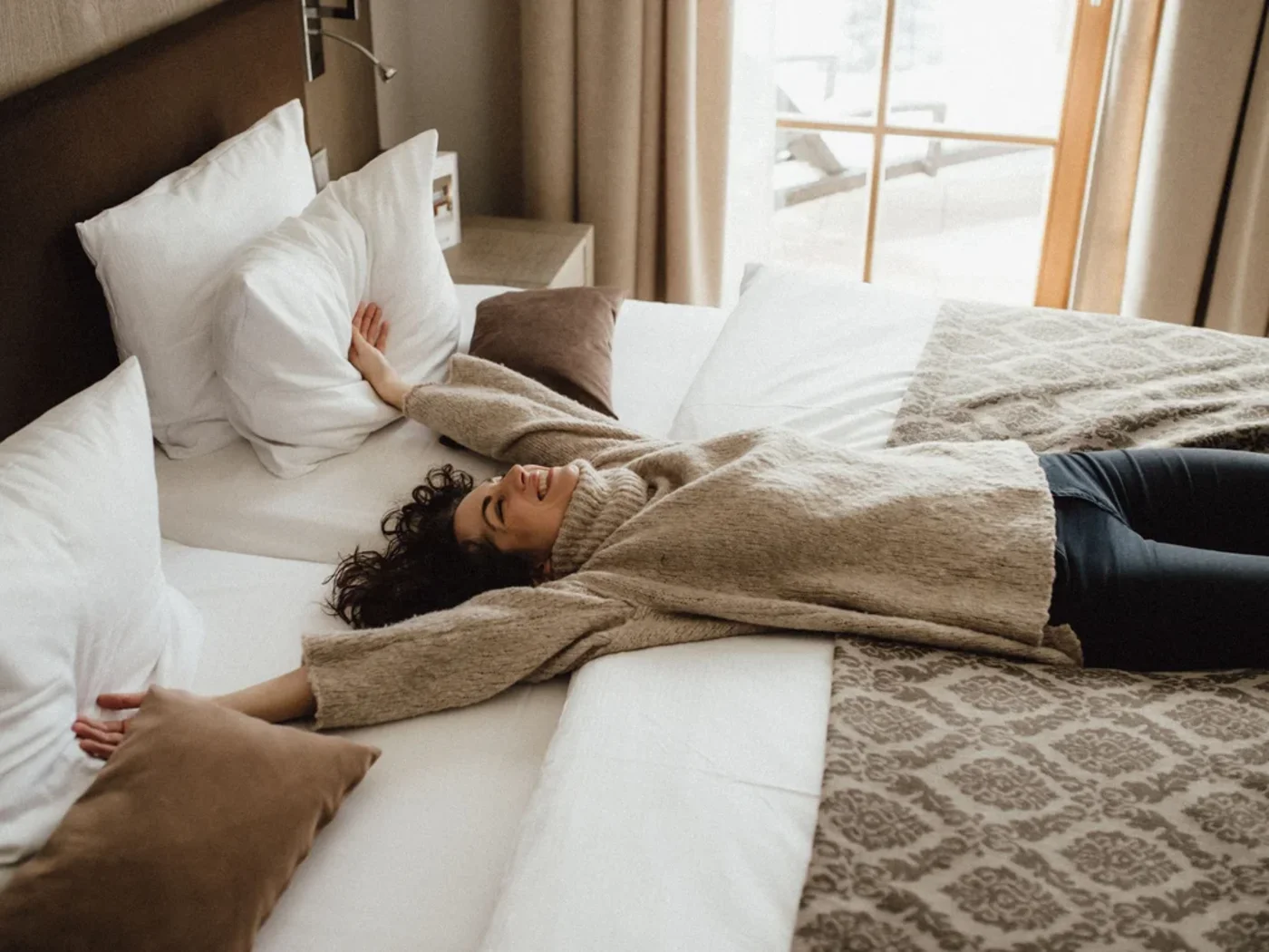 Kitzbühel Adler Suite mit gemütlichem Doppelbett, eleganter Einrichtung und großzügigem Fenster mit Blick auf die verschneite Berglandschaft.