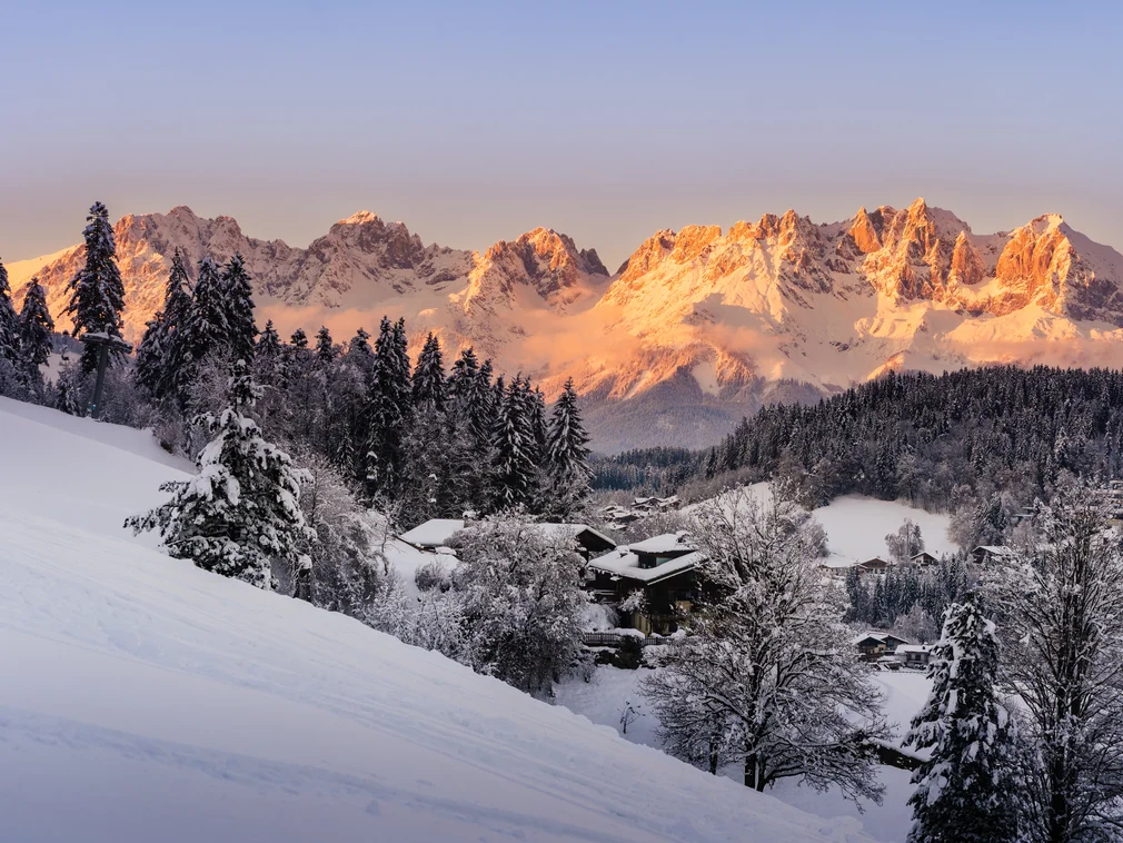 Snow-covered mountains and houses in winter at sunset