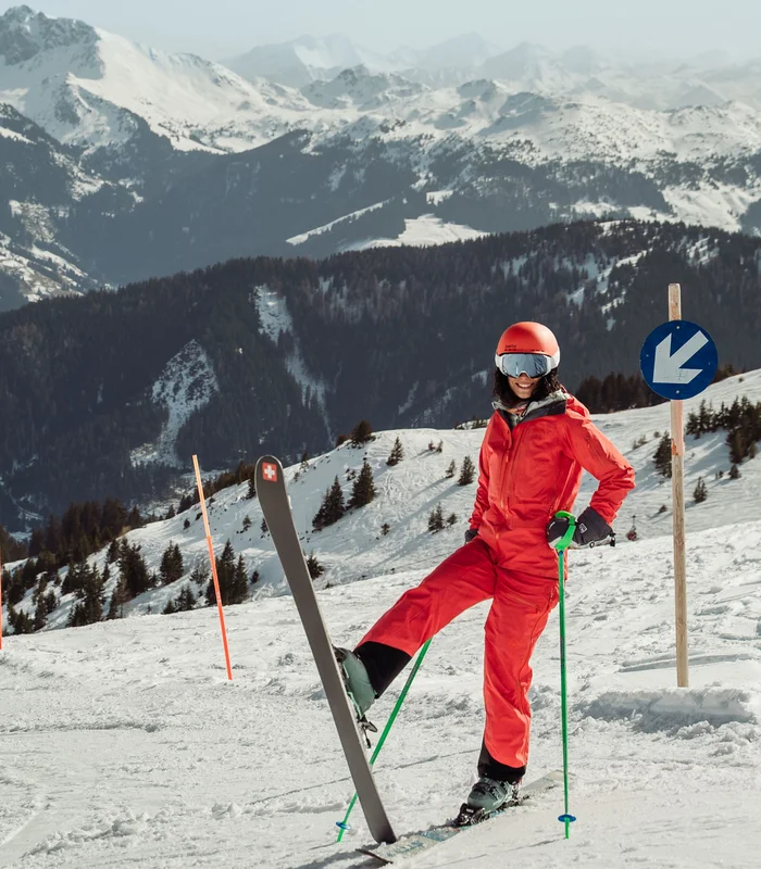 Skier in red outfit on snowy mountain with mountains in background