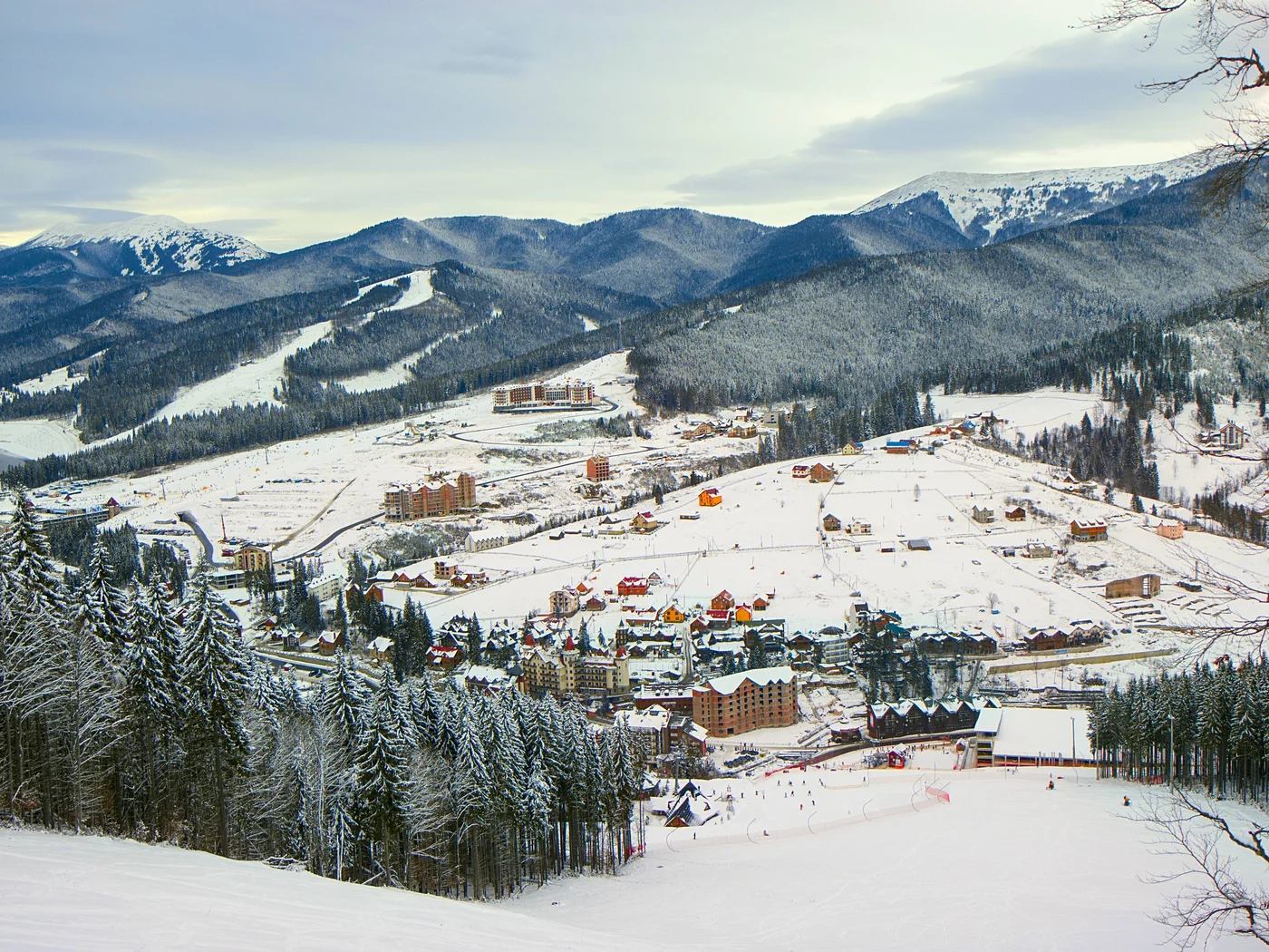 Paesaggio invernale con villaggio innevato e montagne sullo sfondo