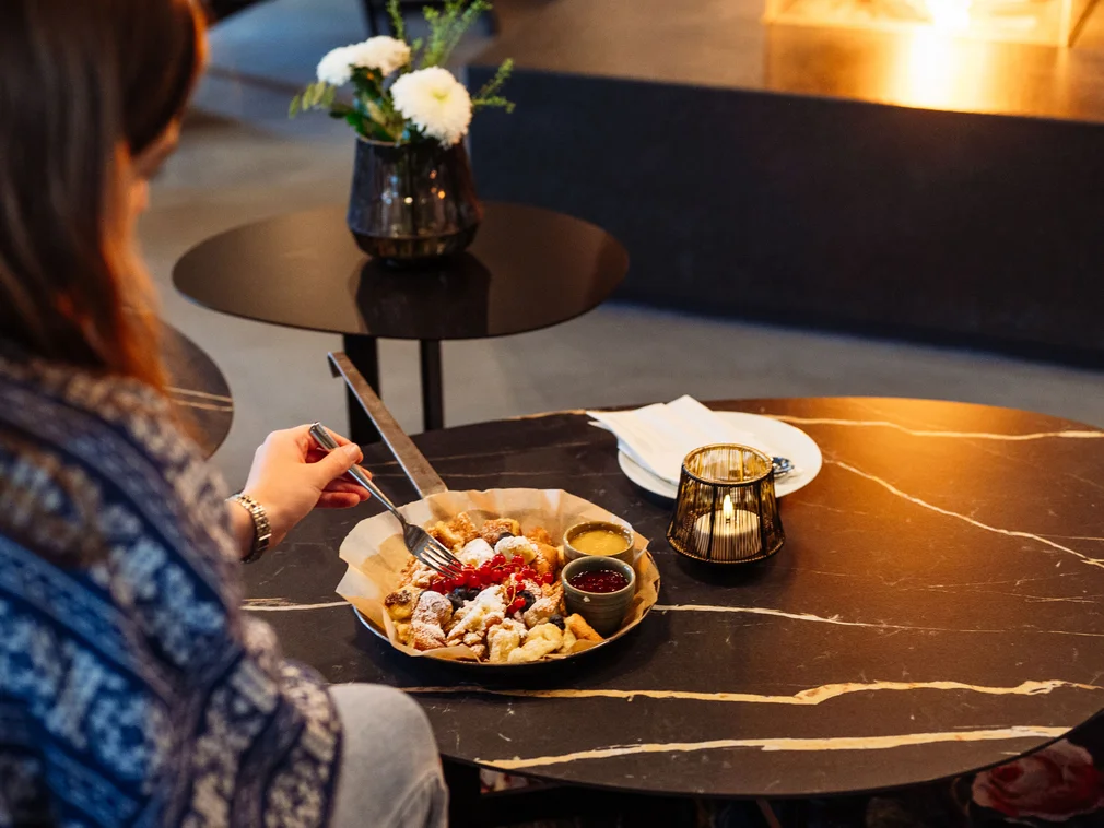 Person eating dessert with fork at a table with candle and flowers