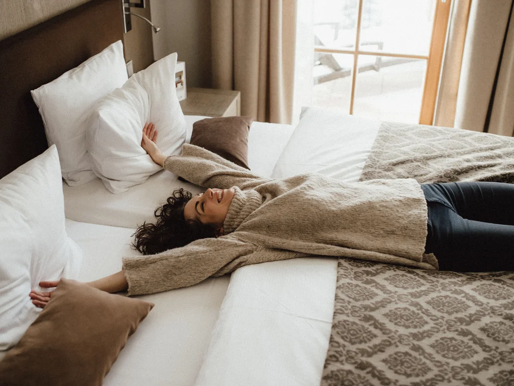 Woman lying relaxed on a cozy bed with light pillows
