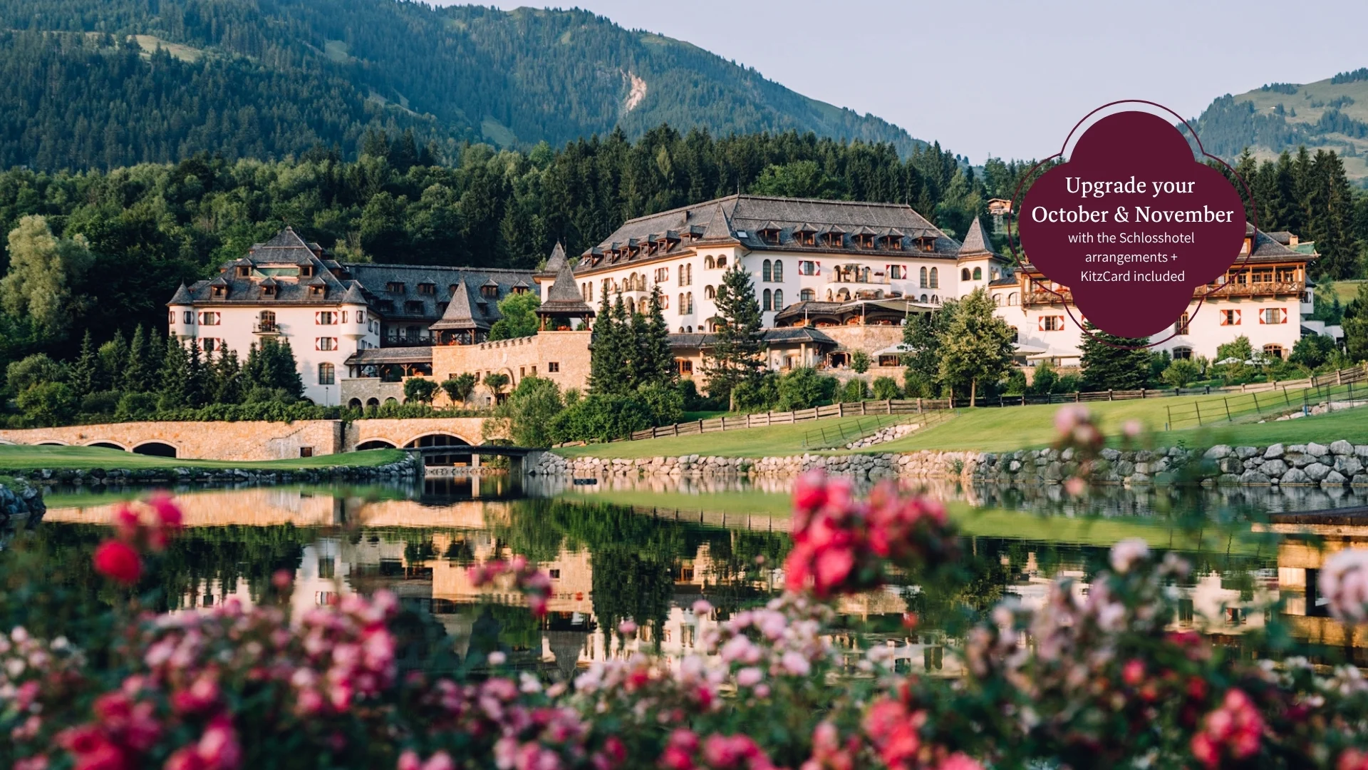Schlosshotel Kitzbühel – a premium experience Lakeside hotel beneath wooded mountains, reflected in the water with flowers in the foreground