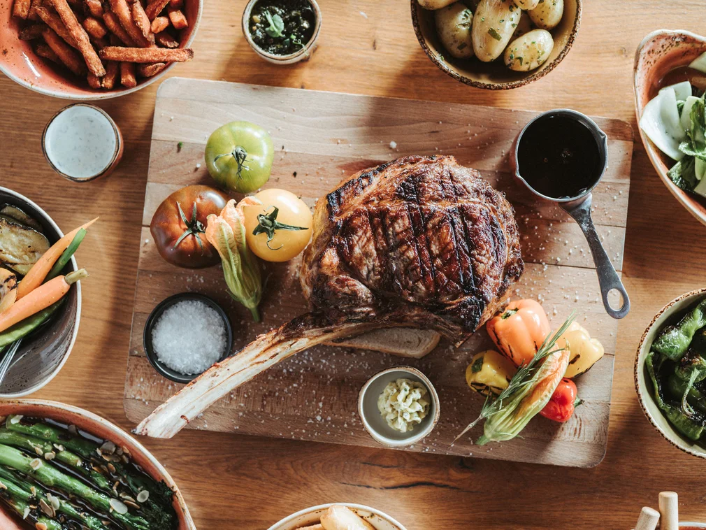 Grilled steak with vegetables and sides on a wooden cutting board