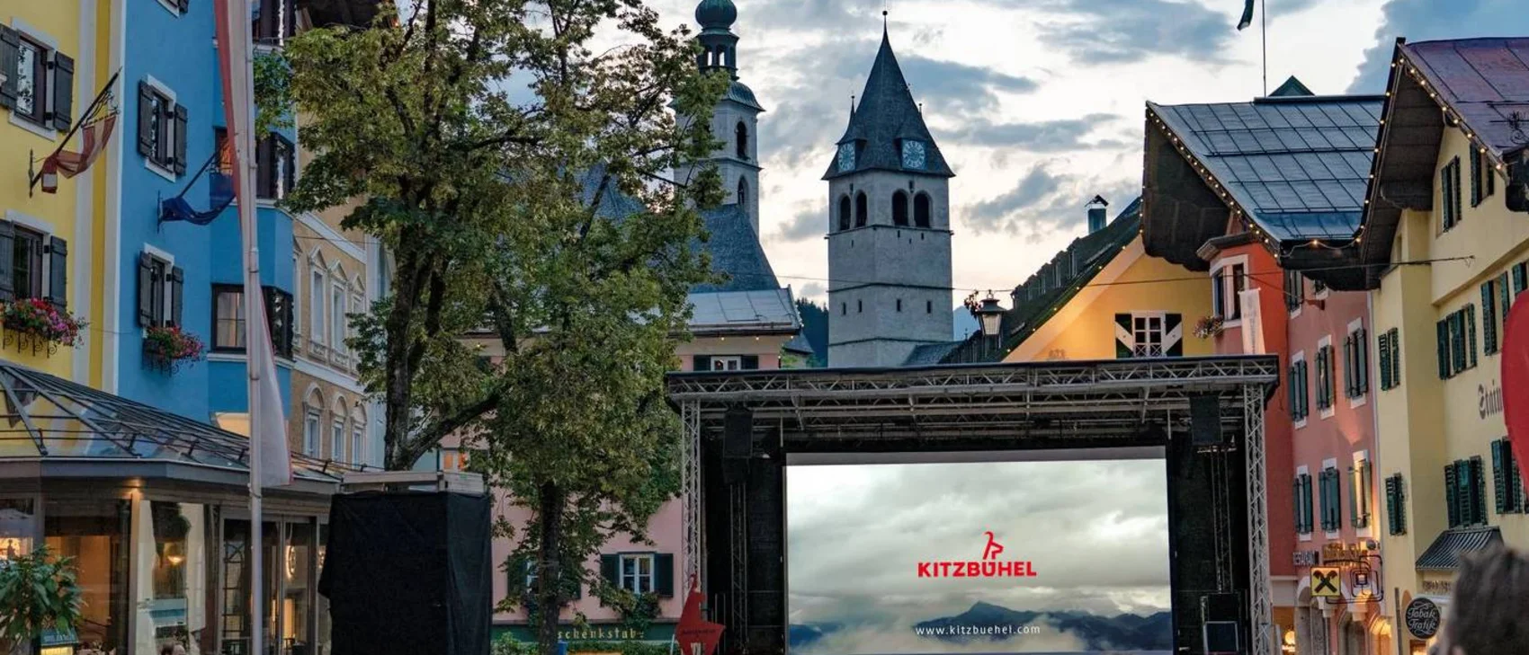 Freiluftkino in Kitzbühel mit Zuschauern und historischen Gebäuden im Hintergrund