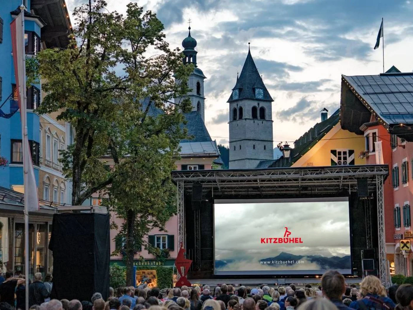 Outdoor cinema in Kitzbühel with audience and historic buildings in the background