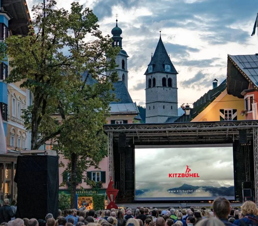 Outdoor cinema in Kitzbühel with audience and historic buildings in the background