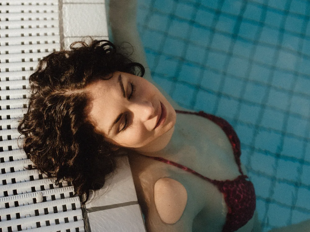 Woman relaxing in pool leaning against the edge of the swimming pool