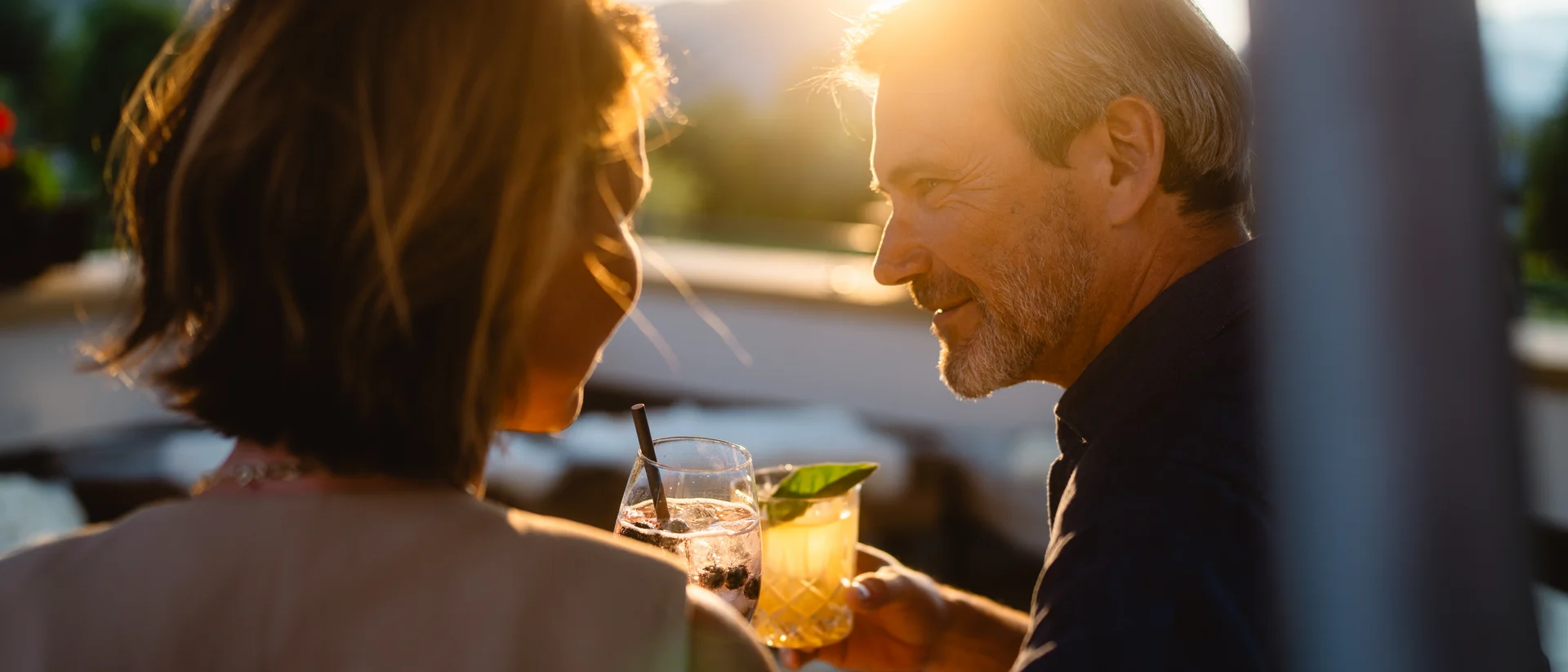 Flitterwochen im Hotel in Österreich | Schlosshotel Kitzbühel Paar genießt bei Sonnenuntergang gemeinsam Drinks auf einer Terrasse