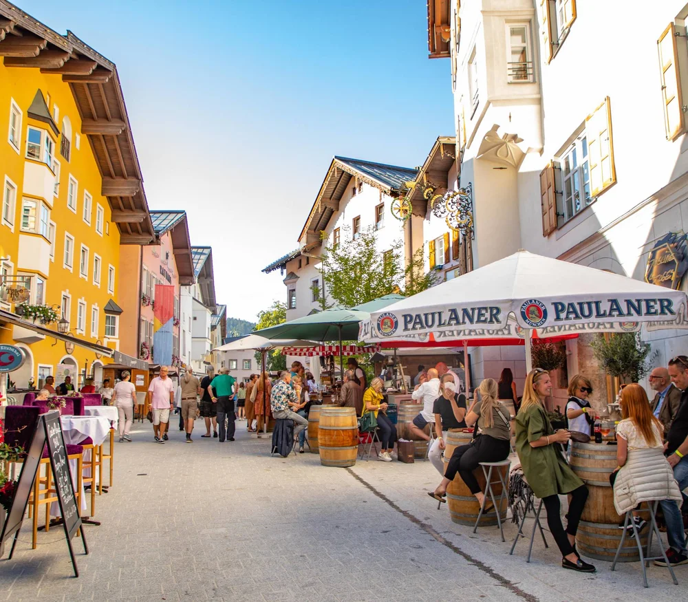 Full Moon Spa Night at Schlosshotel Kitzbühel Busy pedestrian street with cafes and colorful buildings in sunlight