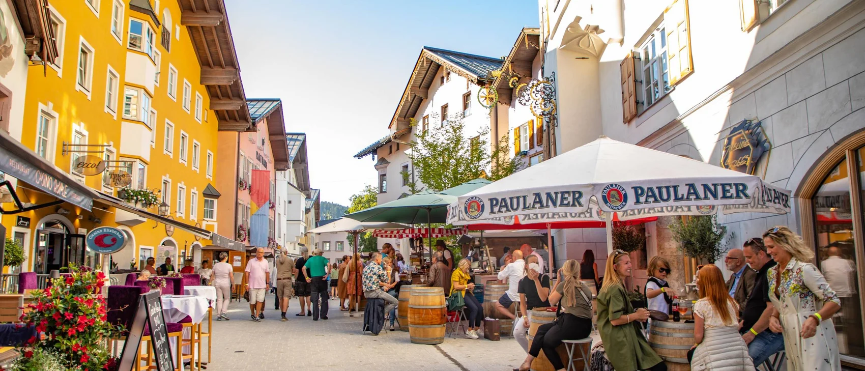 Belebte Fußgängerzone mit Cafés und bunten Gebäuden im Sonnenschein
