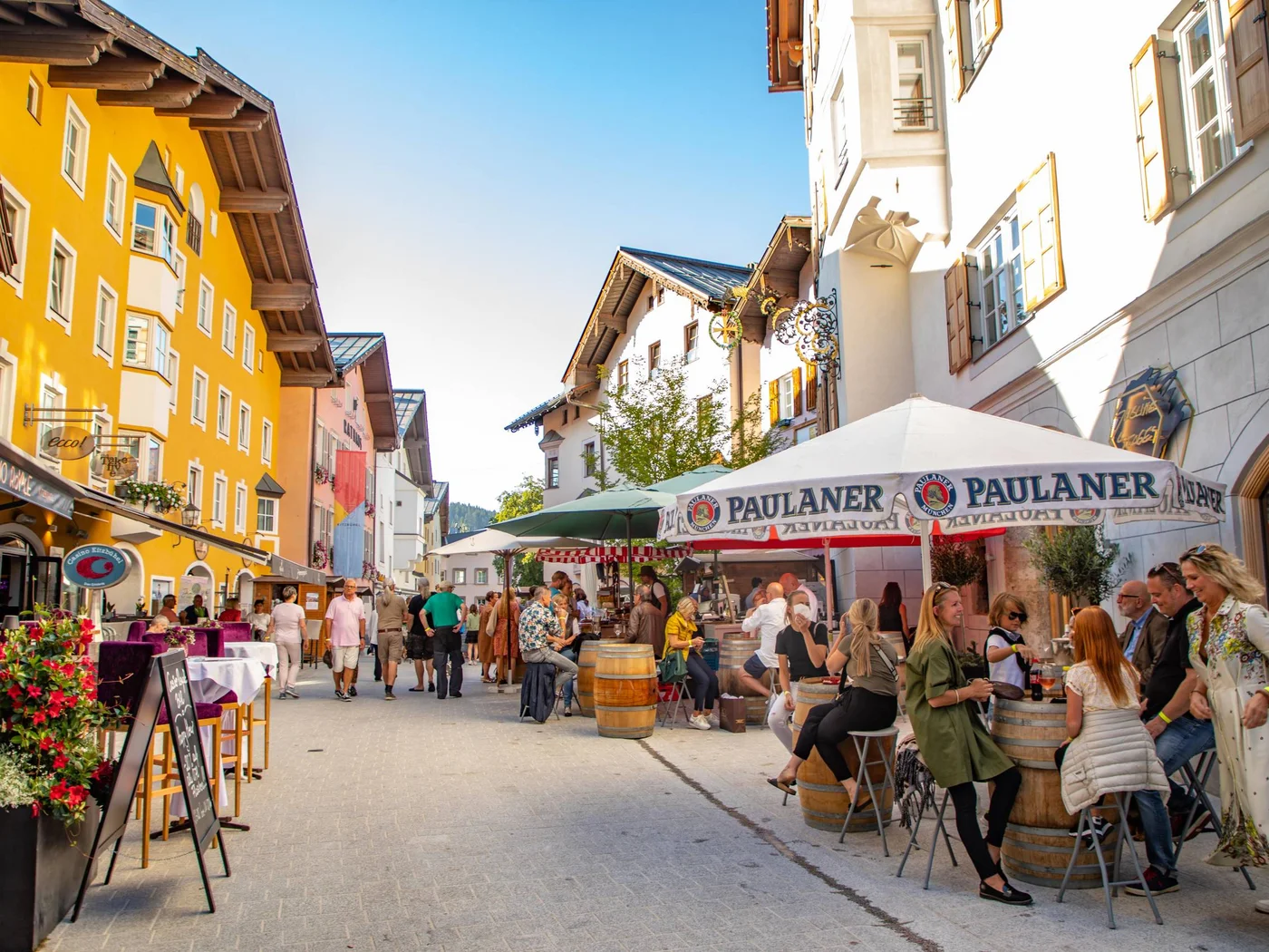 Belebte Fußgängerzone mit Cafés und bunten Gebäuden im Sonnenschein